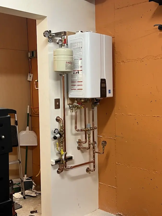 Plumbing technician inspecting water heater connections in Breese